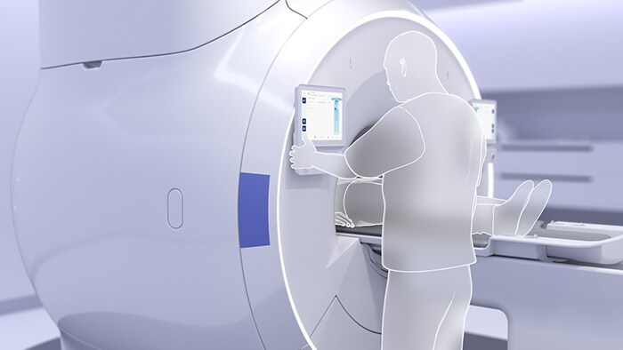 Foto van een radiologiemedewerker die een aanraakscherm voor MRI-beeldvorming gebruikt om automatisch starten met één druk op de knop te activeren