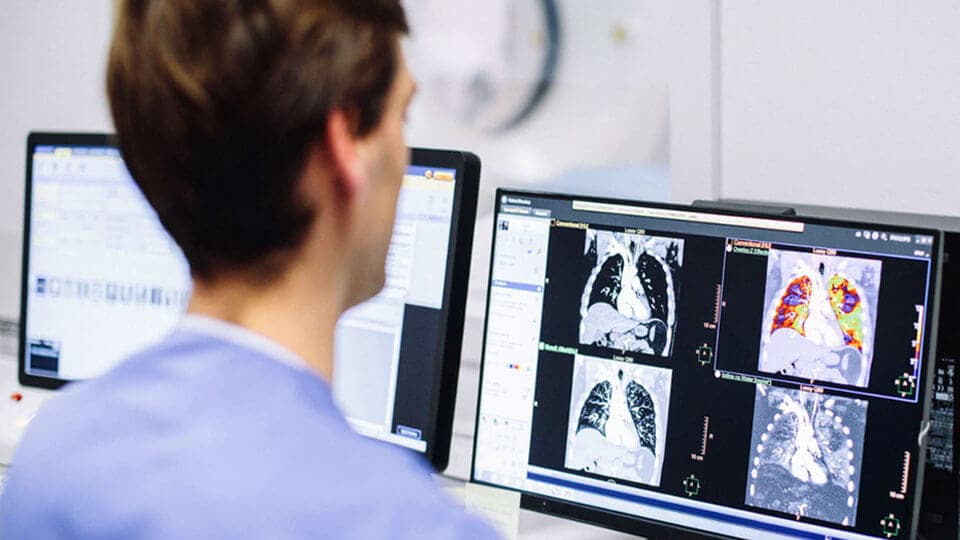 Foto van radiologiemedewerker die klinische CT-beelden op een monitor beoordeelt