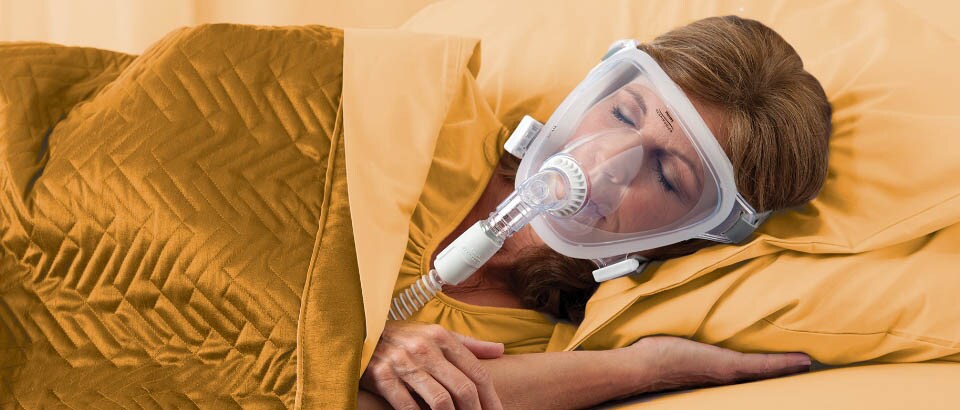 Vrouw in gele kleding slaapt met een masker op dat haar gezicht bedekt