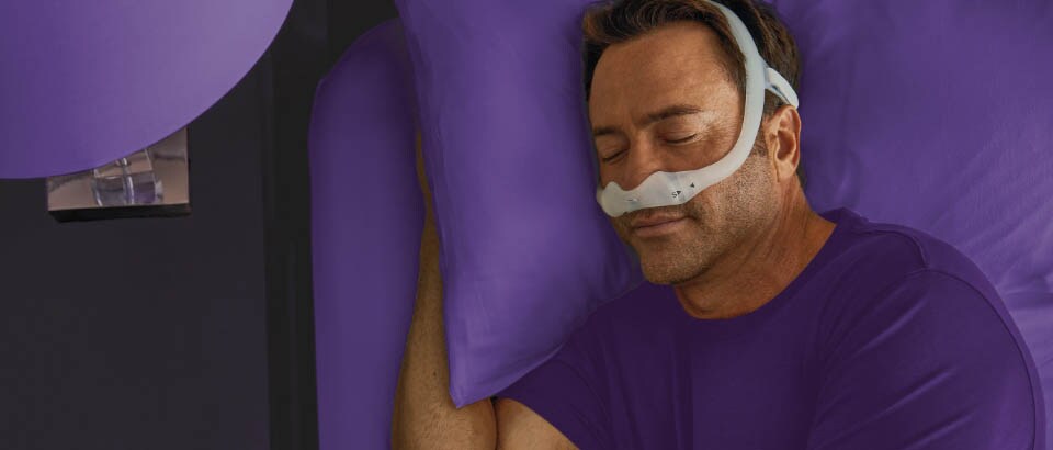 Man met een paars t-shirt slaapt met een masker