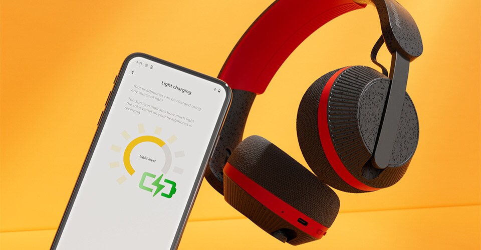 Philips A6219-hoofdtelefoon naast een smartphone met een licht oplaadscherm, tegen een feloranje achtergrond