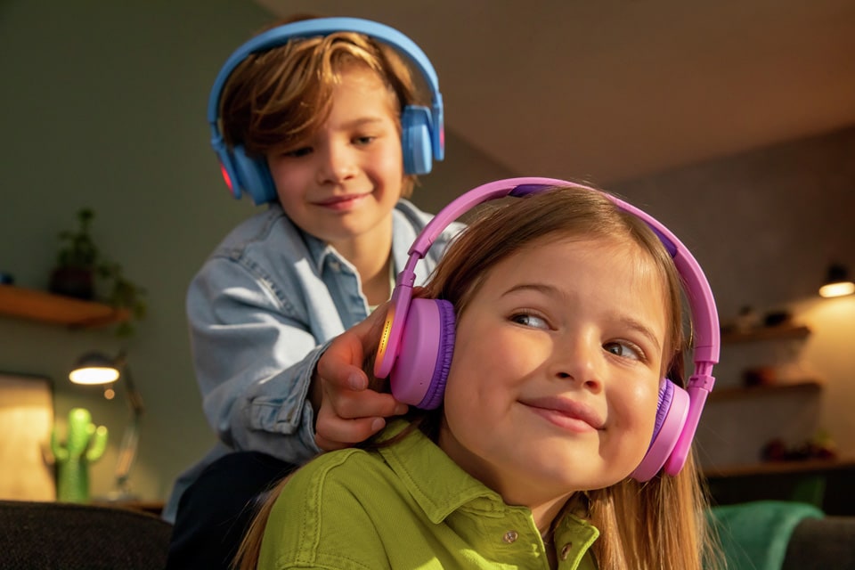 Twee broers en zussen die spelen terwijl ze on-ear koptelefoon voor kinderen gebruiken.