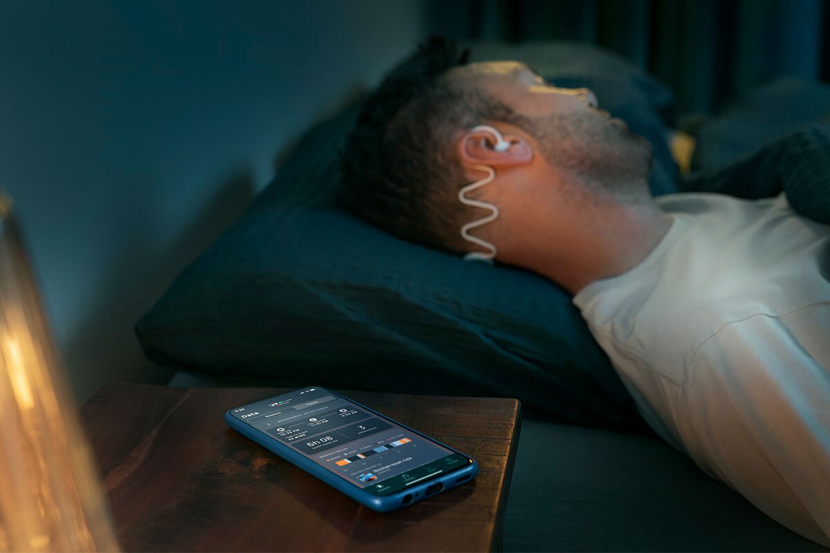 Man slaapt met Philips Sleep Headphones met dunne slaap-oordopjes en de Kokoon-app.