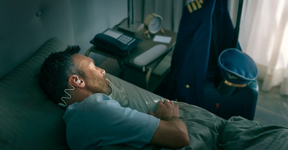 Een man slaapt comfortabel op zijn zij met Philips Sleep Headphones.