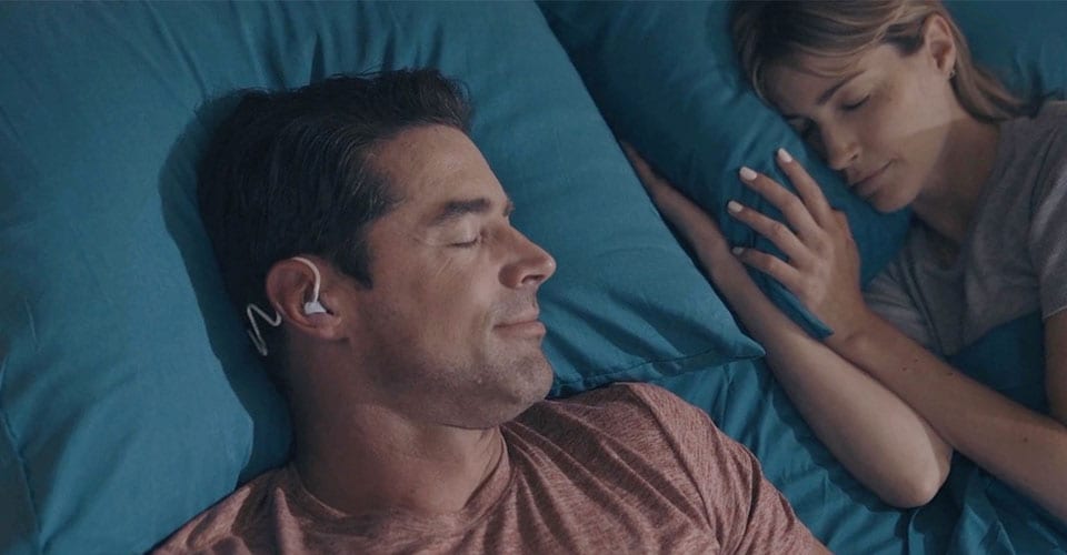 Afbeelding van een man die slaapt met Philips Sleep Headphones om verstoringen te vermijden terwijl hij een bed deelt met een partner.