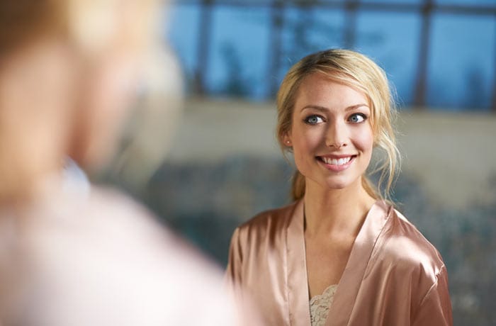 Een vrouw in een ochtendjas lacht en onthult haar hagelwitte tanden.