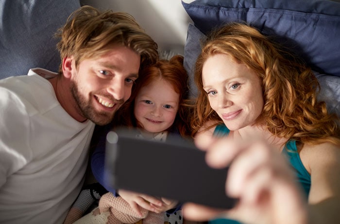 Een vrouw maakt een selfie met haar man en jonge dochter.