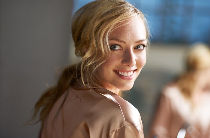 Een jonge vrouw laat haar hagelwitte tanden zien met een grote glimlach.