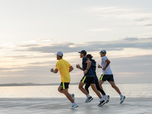 Vier deelnemers aan de run rennen samen op het strand.