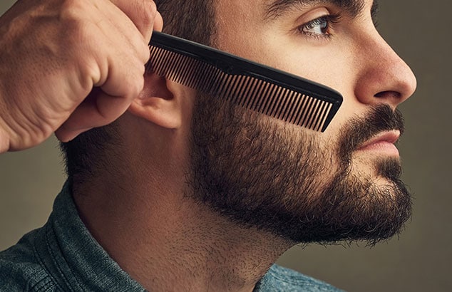 Zijprofiel van man met volle baard die zijn wangharen op hun plaats laat kammen.