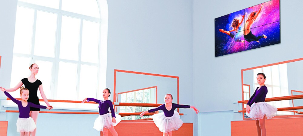 Digitale signage-display aan de muur. Kinderen leren ballet in een kamer